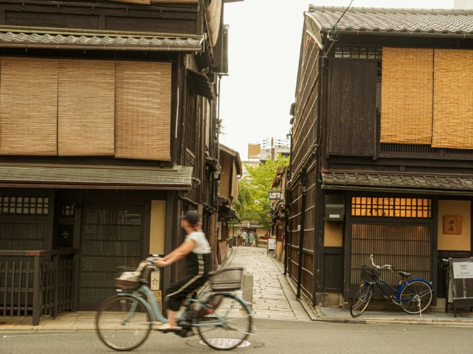 Person rides bicycle down narrow street with old buildings.